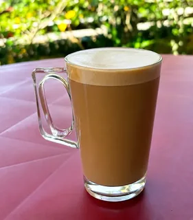 Flat White com microespuma fina servido em caneca alta de vidro
